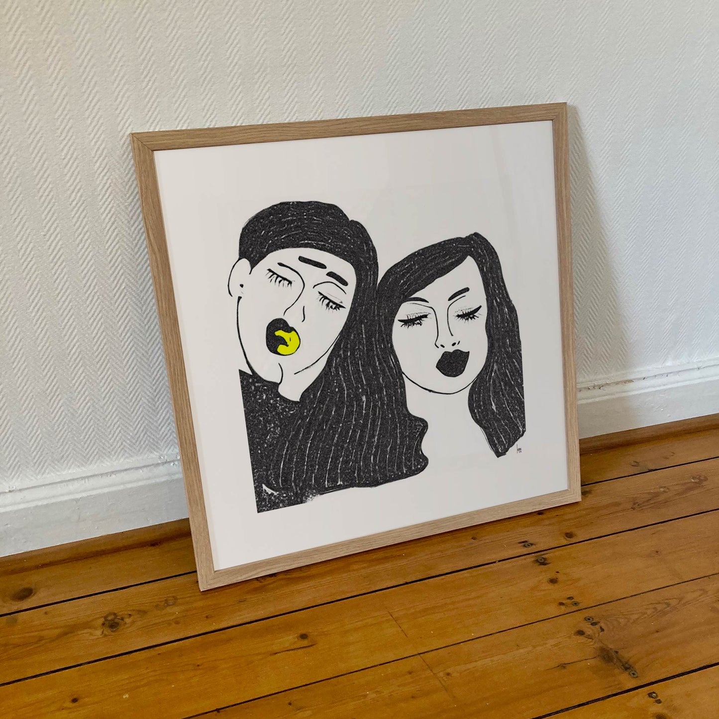 Œuvre 'TRISTAN ET YSEULT' encadrée en 50x50cm, visages enlacés en noir et blanc avec touche jaune, cadre en bois clair, art contemporain, 2023