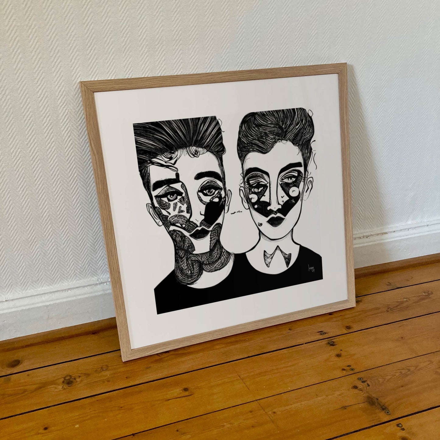 Œuvre 'SACHA & MAYA' encadrée en 50x50cm, visages noir et blanc avec motifs graphiques, cadre en bois clair, art contemporain minimaliste, 2024