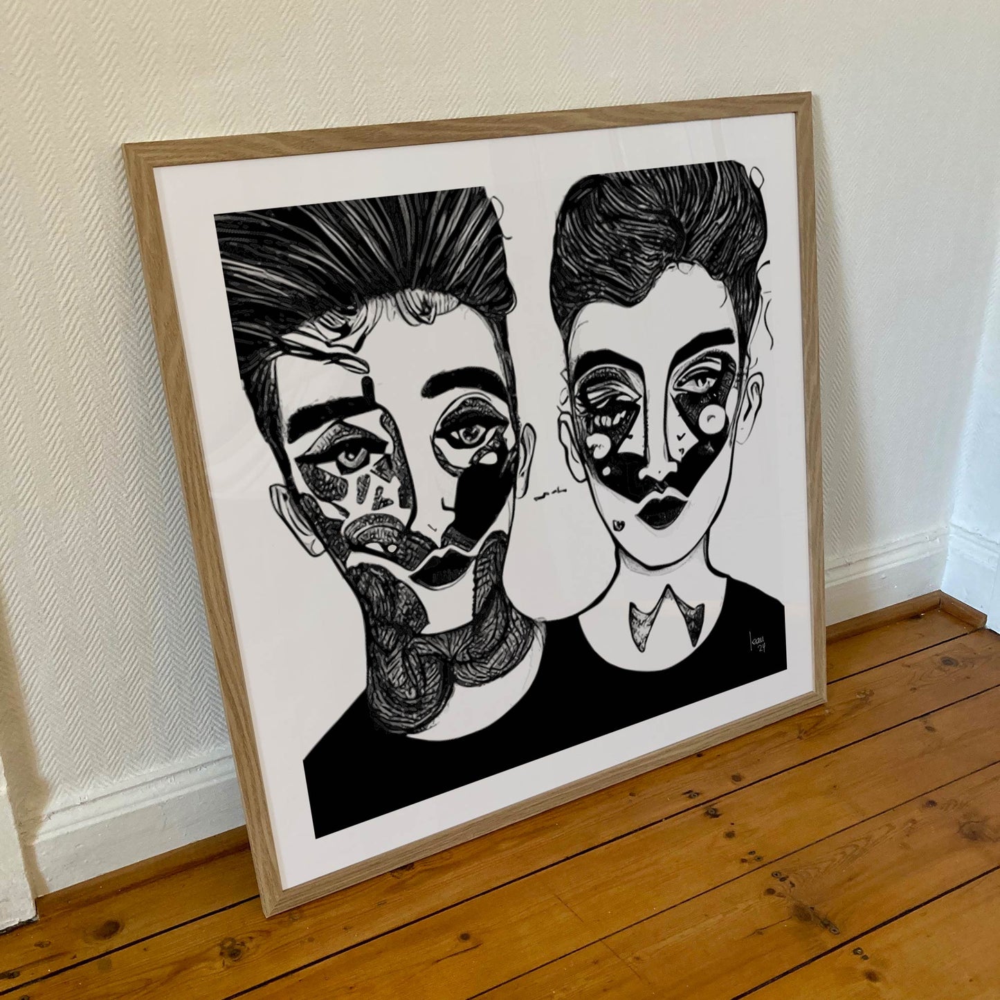 Œuvre 'SACHA & MAYA' encadrée en 70x70cm, visages noir et blanc aux motifs expressifs, cadre en bois clair, style portrait abstrait moderne, 2024