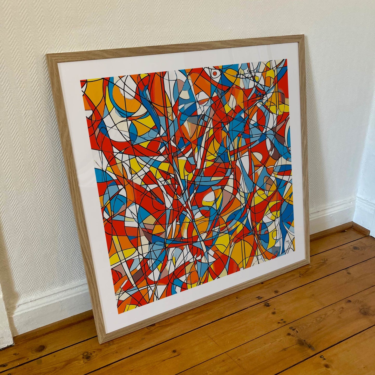Œuvre 'AGITATION' encadrée en 70x70cm, lignes noires et couleurs vives rouge, bleu, jaune, orange, cadre en bois clair, style abstrait moderne, 2024