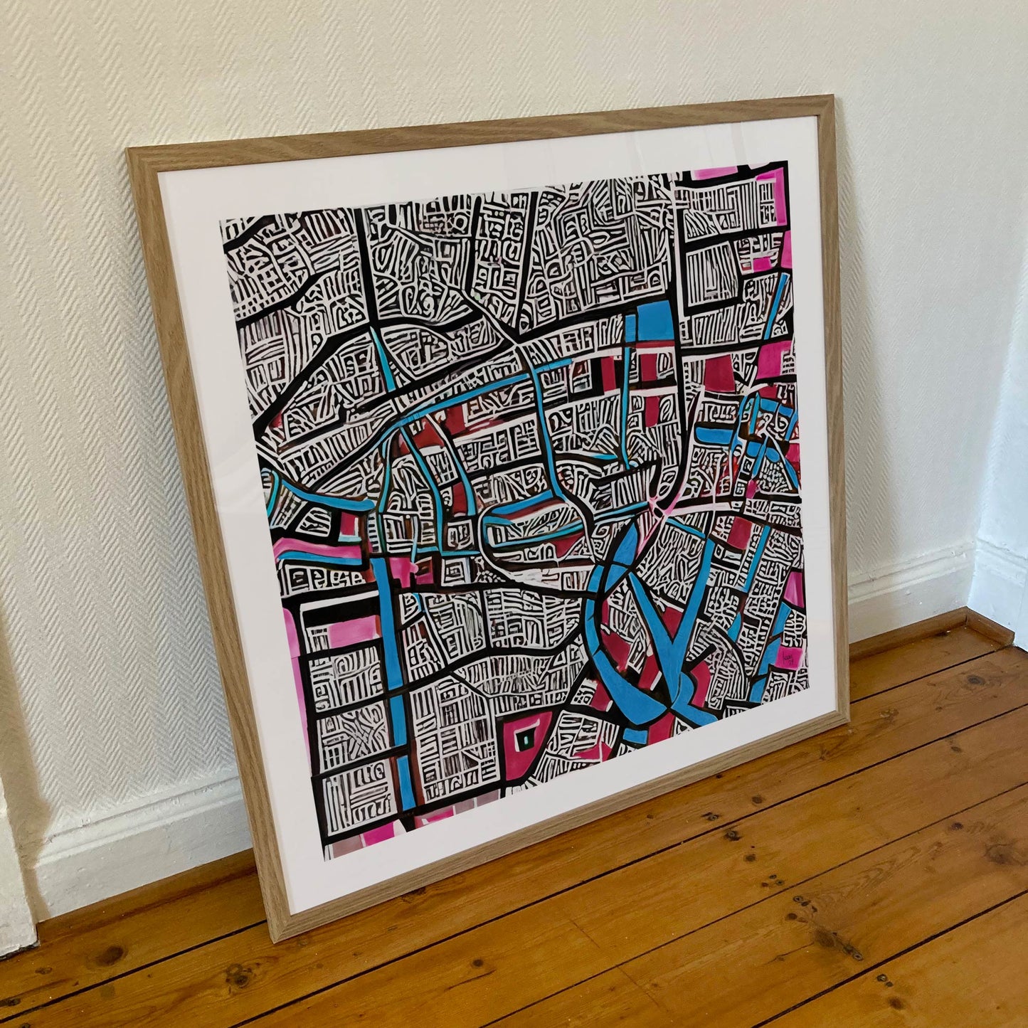 Œuvre 'CONFLUENCE' encadrée en 70x70cm, labyrinthe graphique bleu et rose, cadre en bois clair, style abstrait urbain, 2024