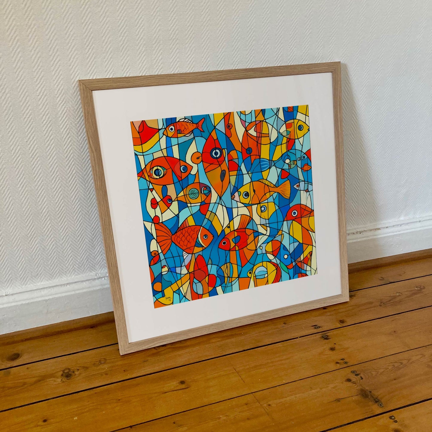 "Aquarium" encadrée en format 50×50 cm, tirage artistique coloré aux motifs aquatiques dynamiques, dans un encadrement sobre en bois clair.