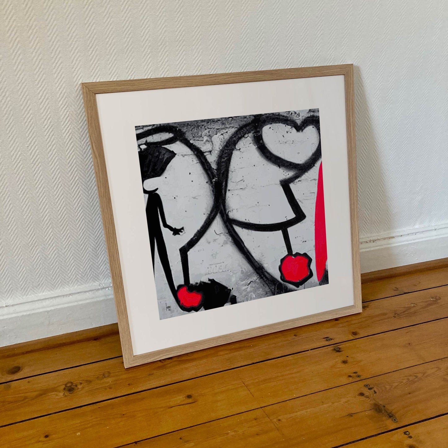 Œuvre "ATTACHES" encadrée en 50x50cm, traits noirs et touches rouges symbolisant les liens humains, cadre en bois clair, style abstrait expressif, 2022